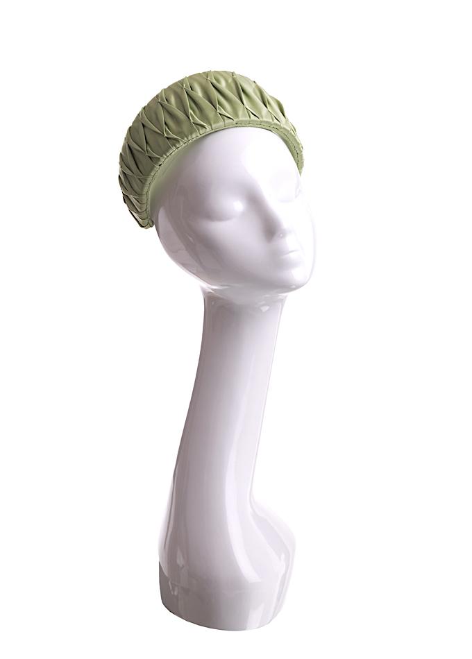 Pale green smocked silk headpiece on mannequin
