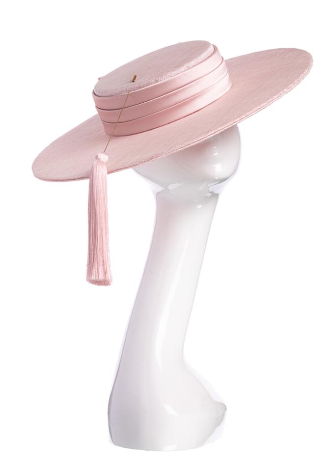 Pale pink wide-brim boater hat with tassel hatpin on mannequin
