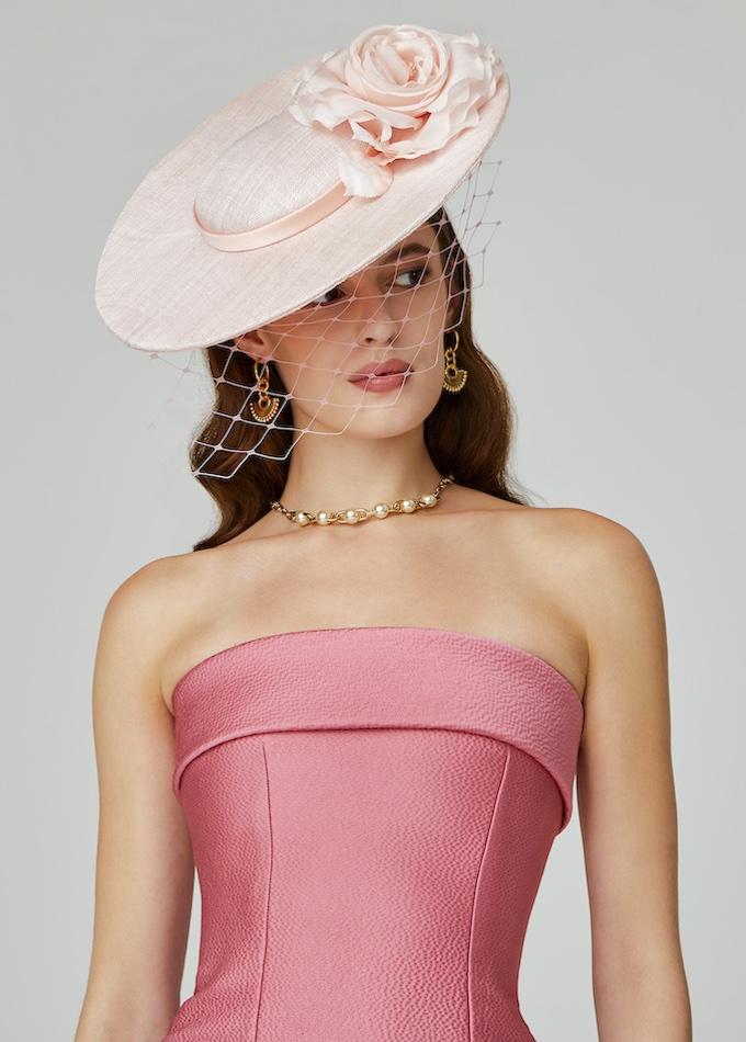 Pale pink disc hat with flower and veil on model