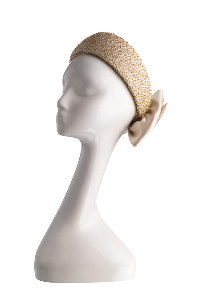 Embellished gold halo headpiece with champagne silk bow on mannequin